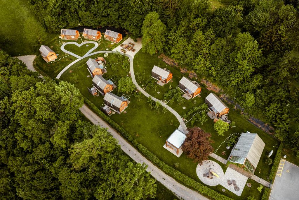 Zračni pogled na naselje lesenih hišk sredi gozda, s potjo v obliki srca